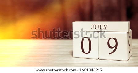 Calendar reminder event concept. Wooden cubes with numbers and month on July 9 with sunlight.