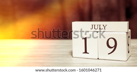 Calendar reminder event concept. Wooden cubes with numbers and month on July 19 with sunlight.