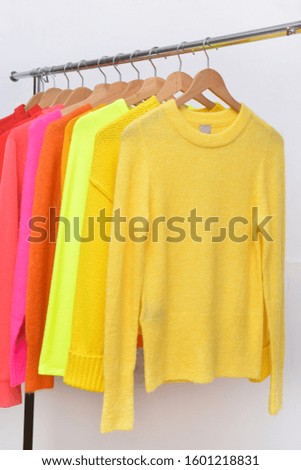colorful knitted with sweater, pink coat on hanger -white background
