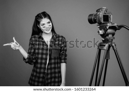Young beautiful Asian hipster woman against gray background