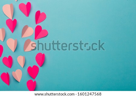 Love (Valentine's day) background or wedding background. Pink and red paper hearts on a blue pastel background. Love concept.