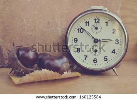 Vintage chestnut and clock on wooden background