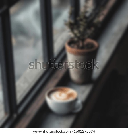 Blurry White cup with steaming hot cappuccino on the wooden table with blurred coffee bar background, coffee shop