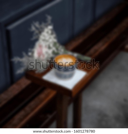 Blurry White cup with steaming hot cappuccino on the wooden table with blurred coffee bar background, coffee shop