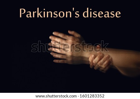 Trembling hands and text PARKINSON'S DISEASE on dark background Royalty-Free Stock Photo #1601283352