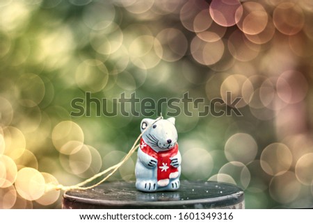 Celebratory ceramic figurine of a rat on a blurred background with a bokeh. New Year symbol. Selective focus.
