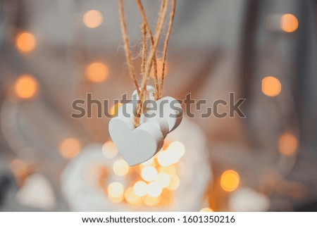 Saint Valentine's day card. White wooden heart with bright bokeh. Hearts with garland lights.