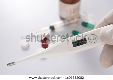 digital thermometer in doctor hand drug and syringe background