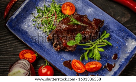 a plate of Pantone color. braised ribs with berry sauce on a plate decorated with seedlings of peas, sunflowers, beets.