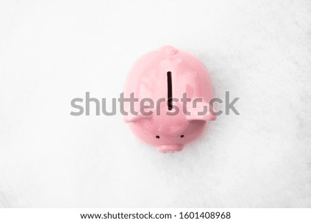 Top view of pink piggy bank stands in the snow on the street with a copyspace
