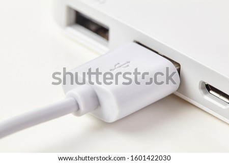 White USB cable into laptop isolated on background. Close up.