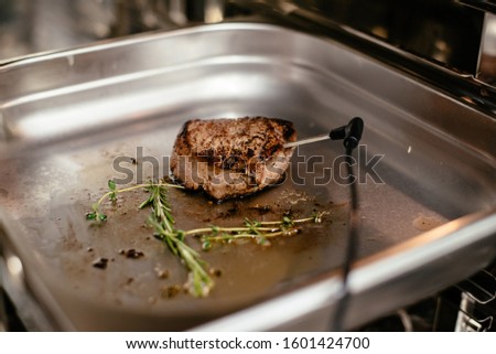 Steak is being prepared. The thermometer measures the temperature of the meat. Selective focus. Film noise