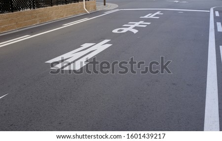 White Japanese kanji and hiragana text on asphalt road in Japan. "Tomare" means stop