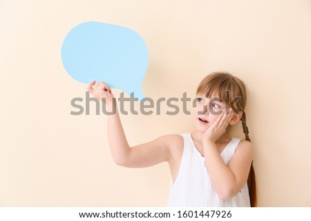 Surprised little girl with blank speech bubble on light background