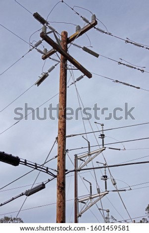 Low angle view of a web of electrical wires and cables and pylons against the winter sky
