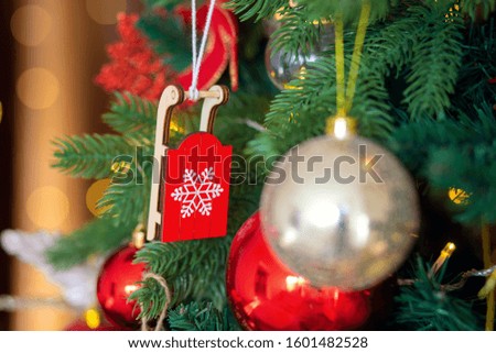 Christmas tree decoration. Wooden toy red sled on a branch close-up.