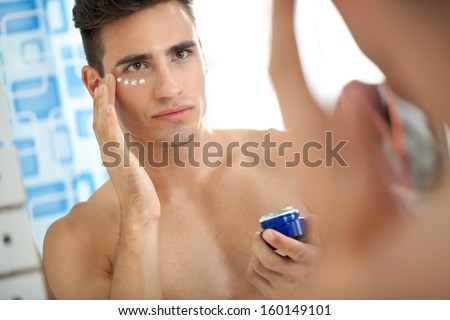 young man applying facial cream  Royalty-Free Stock Photo #160149101