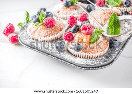 Homemade vanilla muffins or cupcakes with fresh berries on  white marble background