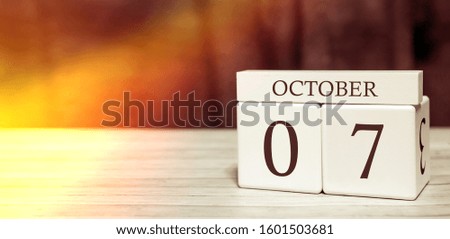 Calendar reminder event concept. Wooden cubes with numbers and month on October 7 with sunlight.