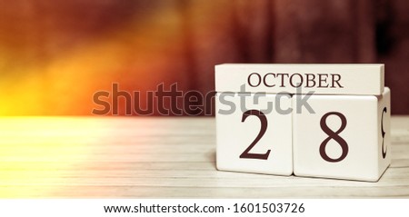Calendar reminder event concept. Wooden cubes with numbers and month on October 28 with sunlight.
