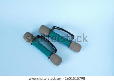 Two grey-green dumbbells on a light blue background