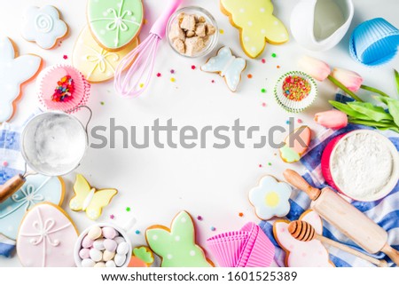 Sweet Easter baking cooking background with traditional Easter bunny and egg cookies, sugar sprinkles, ingredients, utensils. White table background copy space layout