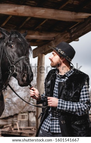 Portrait of a guy in a hat with a black horse.