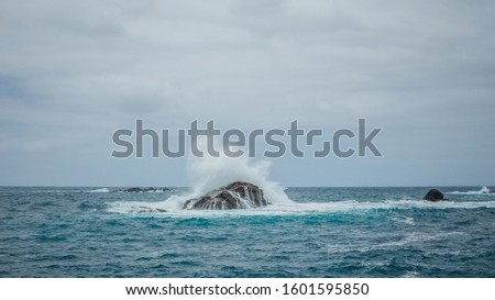 View on a lonely cliff in the middle of the ocean with wild breaking waves 