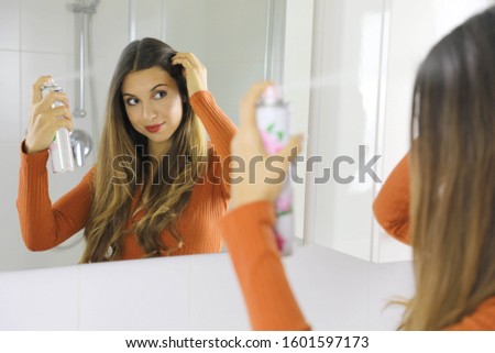 Young woman applying dry shampoo on her hair. Fast and easy way to keep hair clean with dry shampoo. Royalty-Free Stock Photo #1601597173