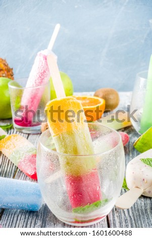 Colorful fruit ice cream popsicle. Juicy gelato lollypops on sticks, with different fresh tropic fruits, wooden background copy space