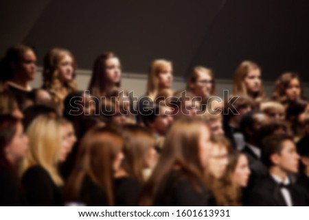 Abstract blur of students singing on stage inside auditorium. Royalty-Free Stock Photo #1601613931
