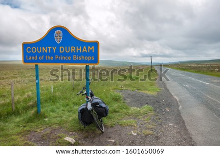 A touring bike leaning against a signpost on the border of County Durham, northern England Royalty-Free Stock Photo #1601650069