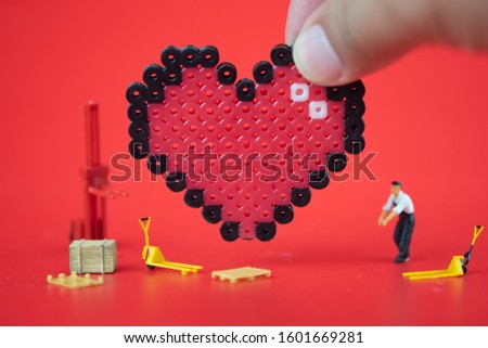 Miniature Worker team and man hand create heart on red background. Love concept for Valentine's day
