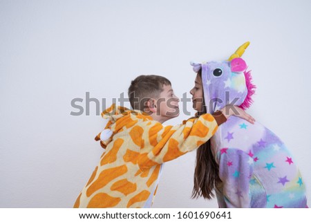 Side view portrait of happy children, boy and girl, brother in giraffe pajamas put his hands on sister's shoulders, playfull children looking at each other