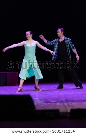 A pair of dancers a man and a woman perform in a theater on stage in a dance musical show.