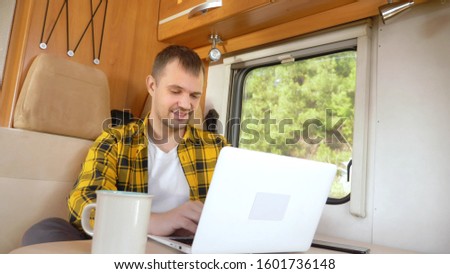 man using his laptop sitting at a table in the motorhome. Royalty-Free Stock Photo #1601736148