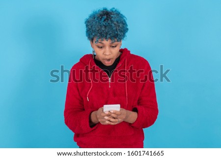 young woman with mobile phone isolated on blue background with space for text