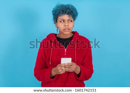 young woman with mobile phone isolated on blue background with space for text
