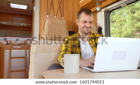 man using his laptop sitting at a table in the motorhome. Royalty-Free Stock Photo #1601744011