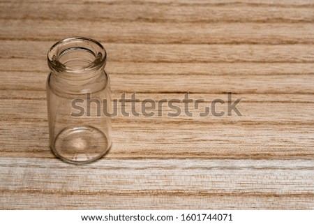 standing tiny shiny laboratory bottle on a light wooden surface