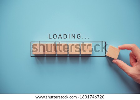 Loading, hand putting wood cube in progress bar. Royalty-Free Stock Photo #1601746720