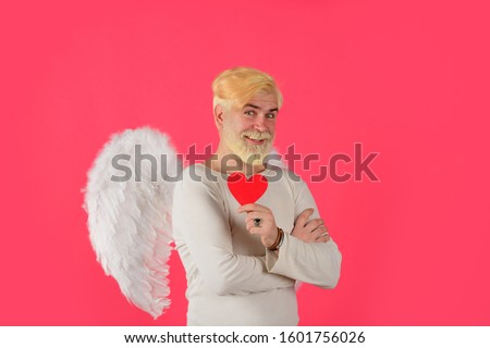 Handsome angel Cupid. Love concept. Valentine angel. Bearded man with angel wings. Valentines day card. Valentines Day. Angel man with white wings. Cupid holds valnetine's heart. Valentines cupid.