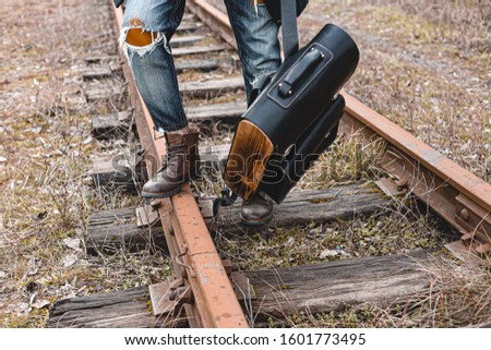 A guy in suede autumn boots on the railway. The concept of hiking, travel practical clothes, shoes.