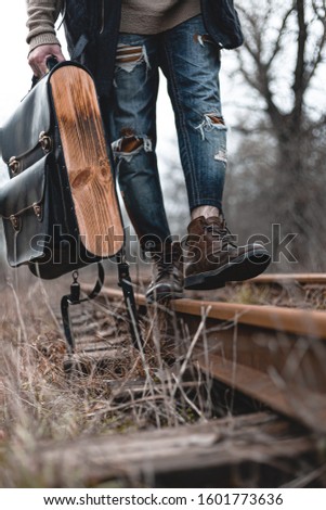 A guy in suede autumn boots on the railway. The concept of hiking, travel practical clothes, shoes.