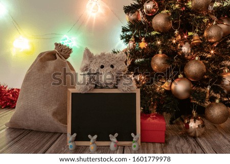 Decorated Christmas and New Year tree on a wooden table, with glowing balls on the background.  Chinese New Year concept with big toy mouse / rat and small wooden mice / rats and a blackboard. 