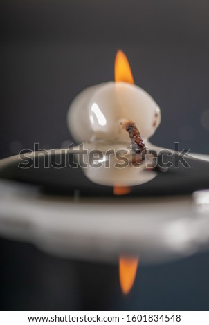 beautiful reflection of a white candle that is still burning in a sleeping position, macro photography