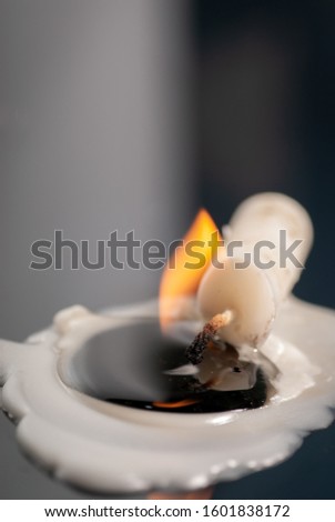 close up of a white candle that is still burning in a sleeping position, macro photography