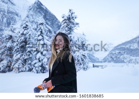 beautiful smiling young woman in wintertime outdoor. Winter concept.Winter holiday. Happy girl travel, happy Hollidays. new year. Alberta lake Luise.red lips at winter view of mountains.smiley face
