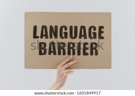 The phrase " Language
barrier " on a banner in men's hand. Human holds a cardboard with an inscription. Speak. Communication. Conversation. Education. Study