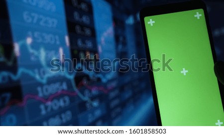 Green screen smartphone, vivid stock market chart as  blue background. Stock market concept.